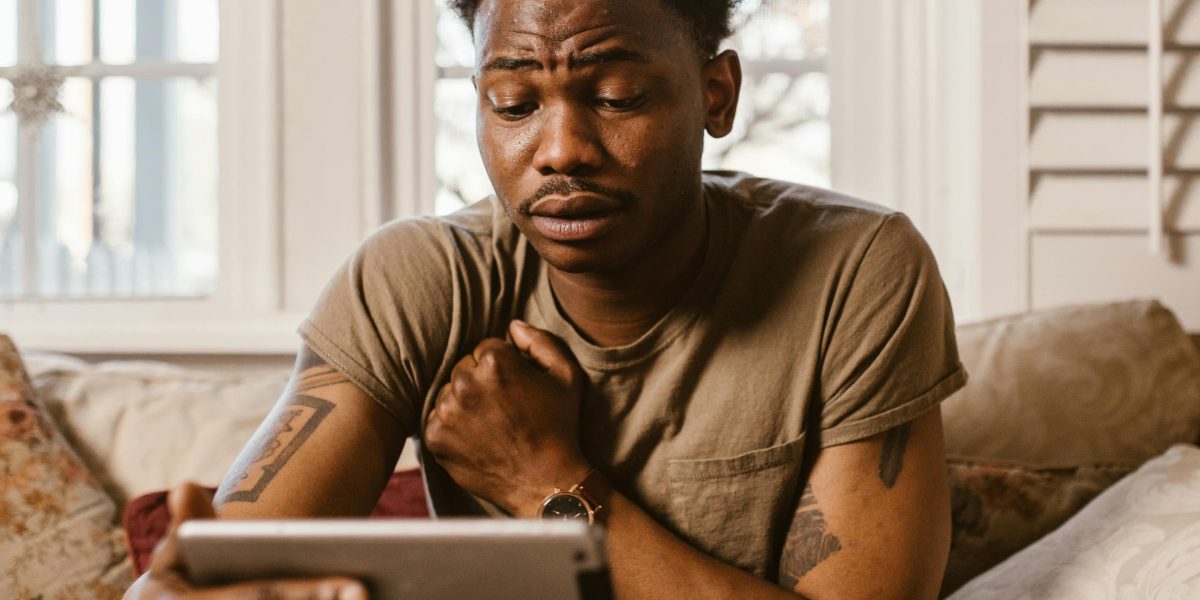 A person intently watching or reading news on a tablet with a thoughtful, questioning expression.