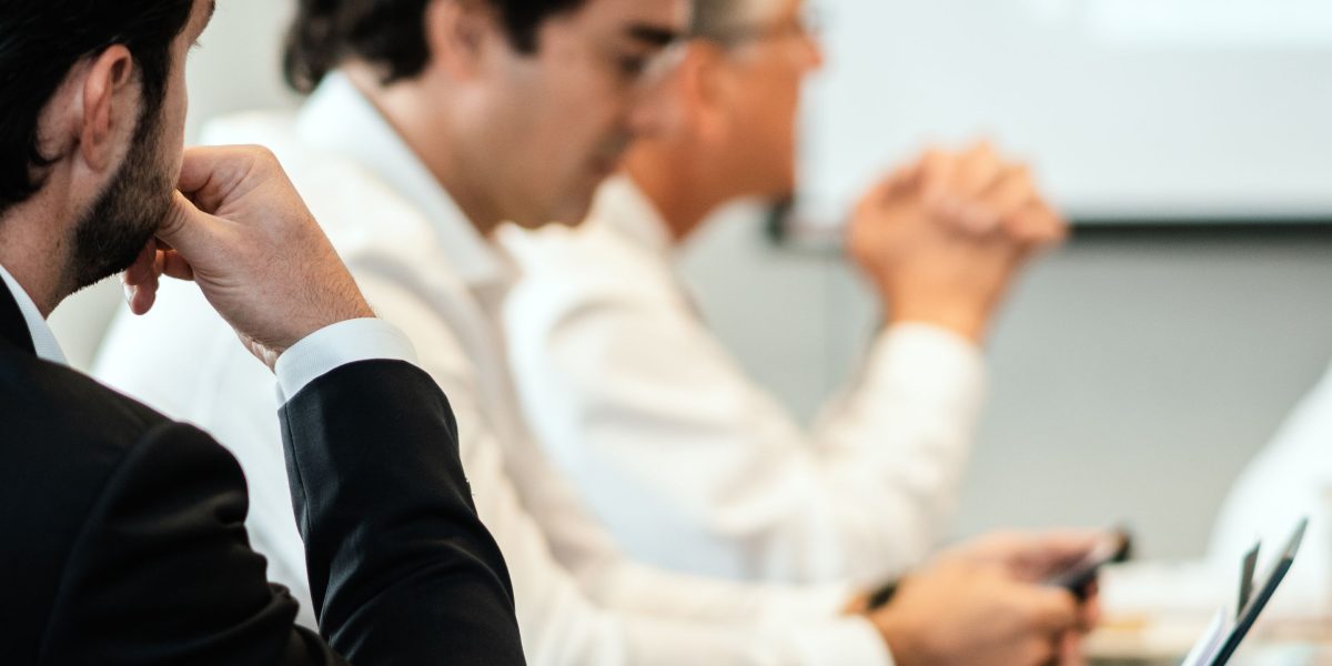 A group of professionals in a boardroom discussing strategic plans related to policy changes.